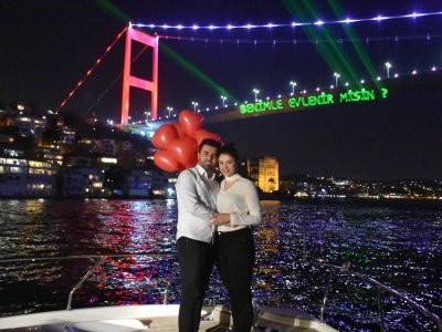 Marriage proposal on a private yacht in Istanbul with Bosphorus Bridge laser lights saying "Will you marry me?"